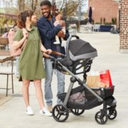 Interracial family on a sidewalk with father holding a baby and mother with her hand on the stroller image number 3