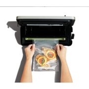 hands taking out bag of sealed orange and chicken from vacuum sealer image number 3