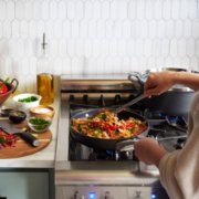 Person cooking food in pan on stovetop image number 5