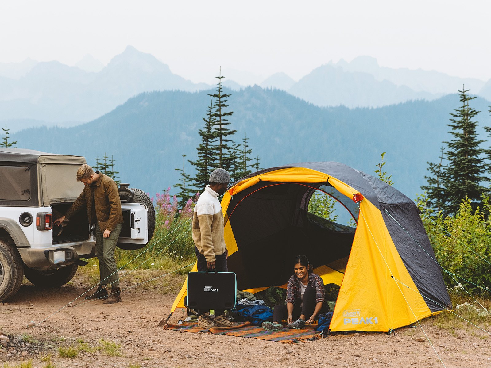 outdoor campsite with three hikers and yellow and gray tent