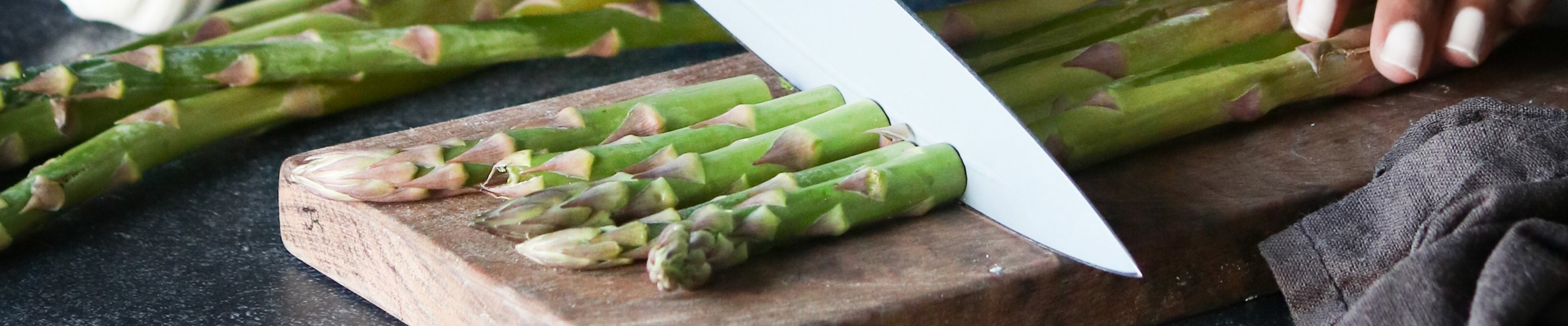 asparagus being cut on cutting block