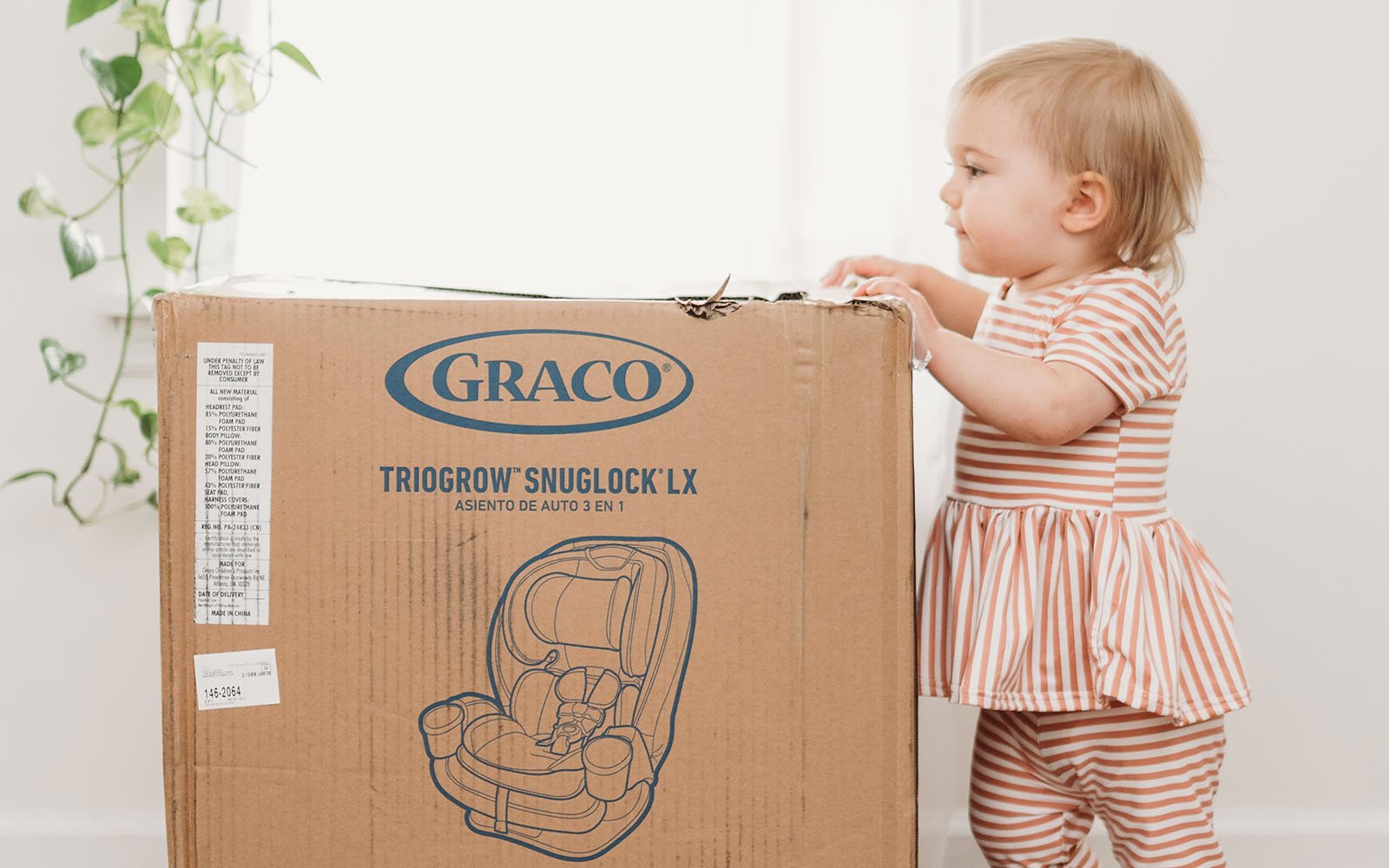 Baby standing next to cardboard box