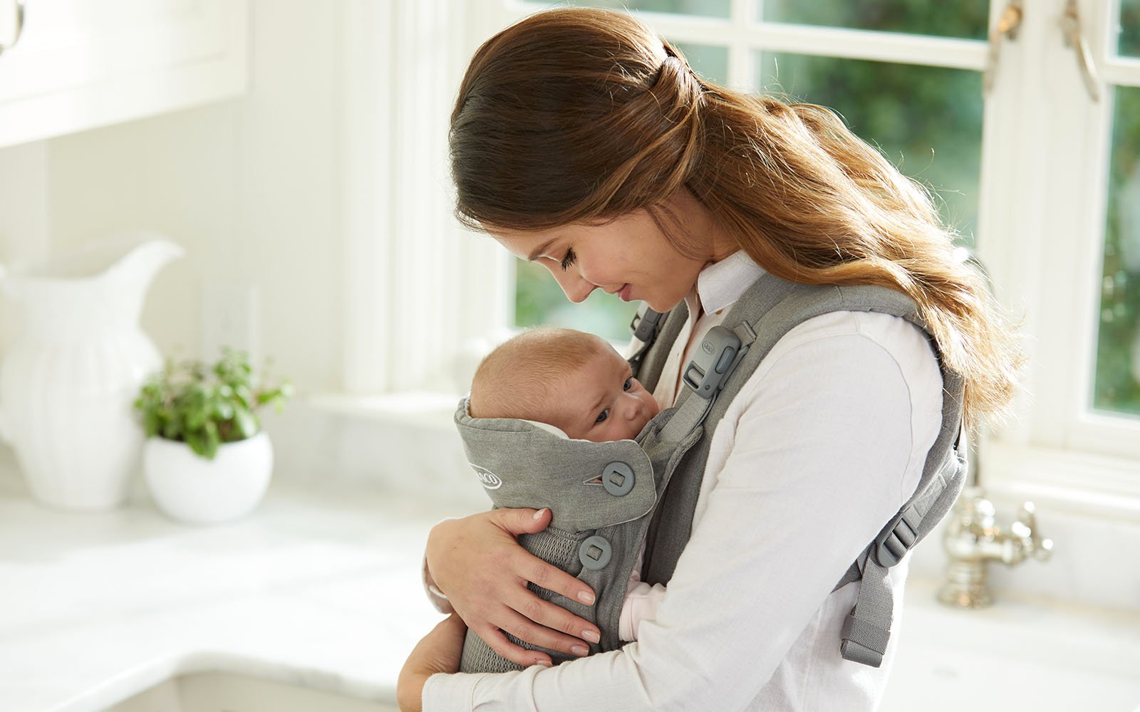 woman holding baby to chest in wearable baby carrier