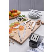 knives spread out on cutting board with vegetables next to knife block image number 6