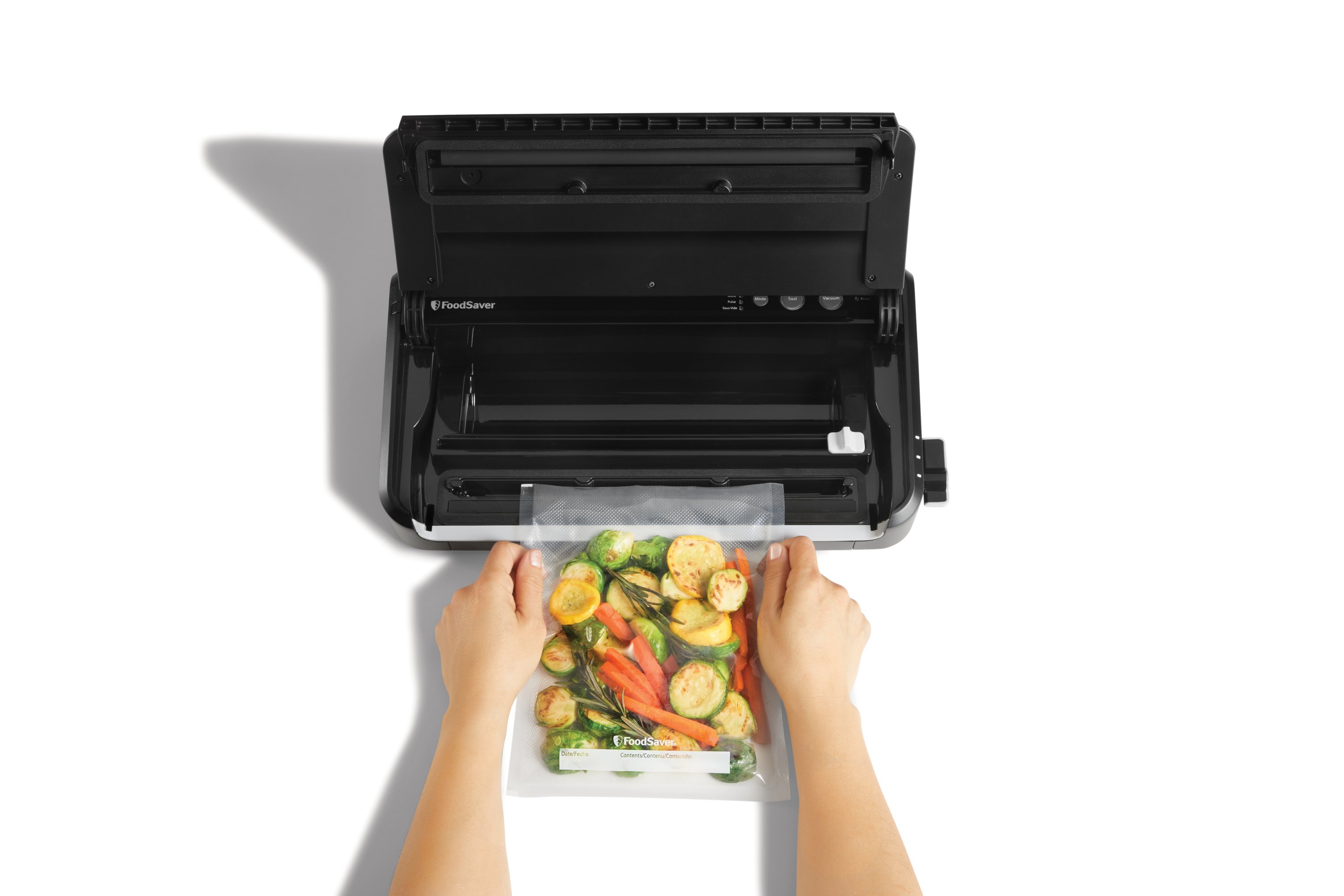 https://newellbrands.scene7.com/is/image/NewellRubbermaid/SAP-foodsaver-FM2900-step-1-with-food-overhead-with-talent-1_White