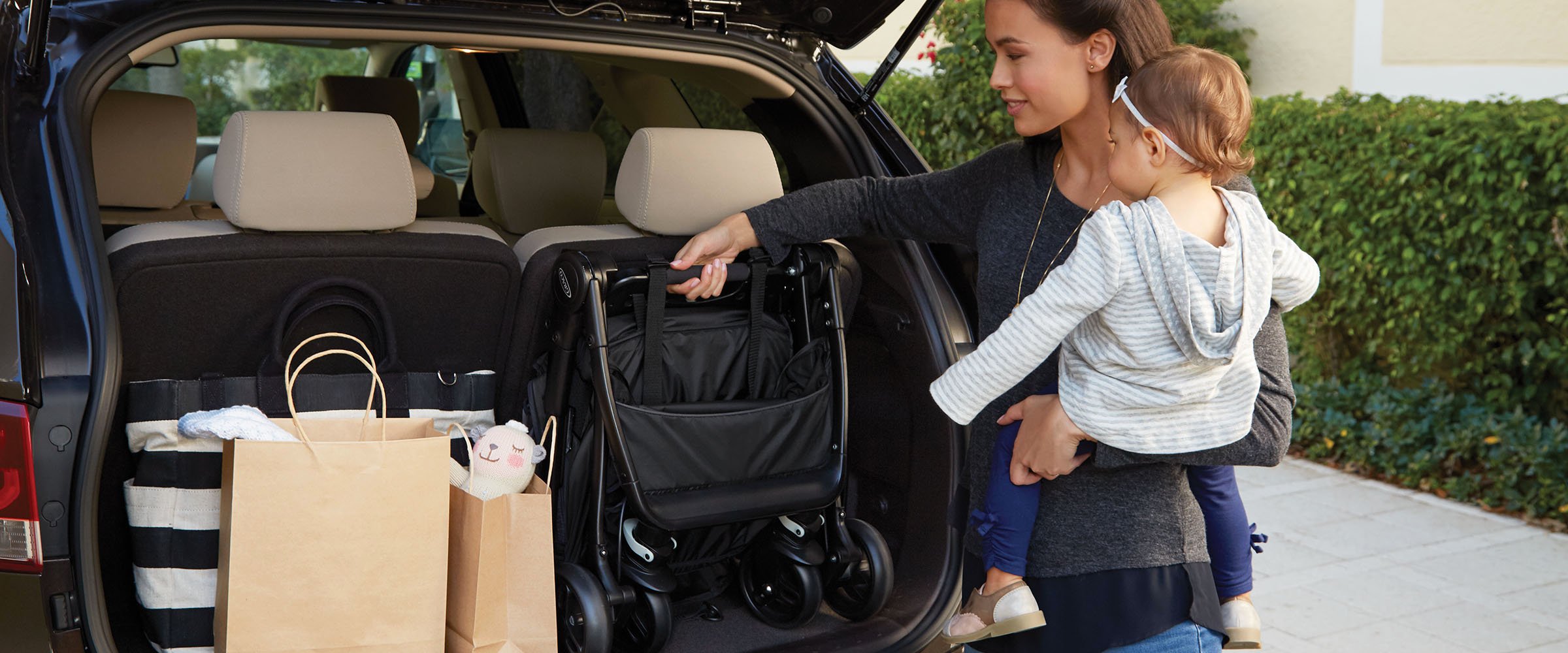 child and mom taking stroller out of trunk
