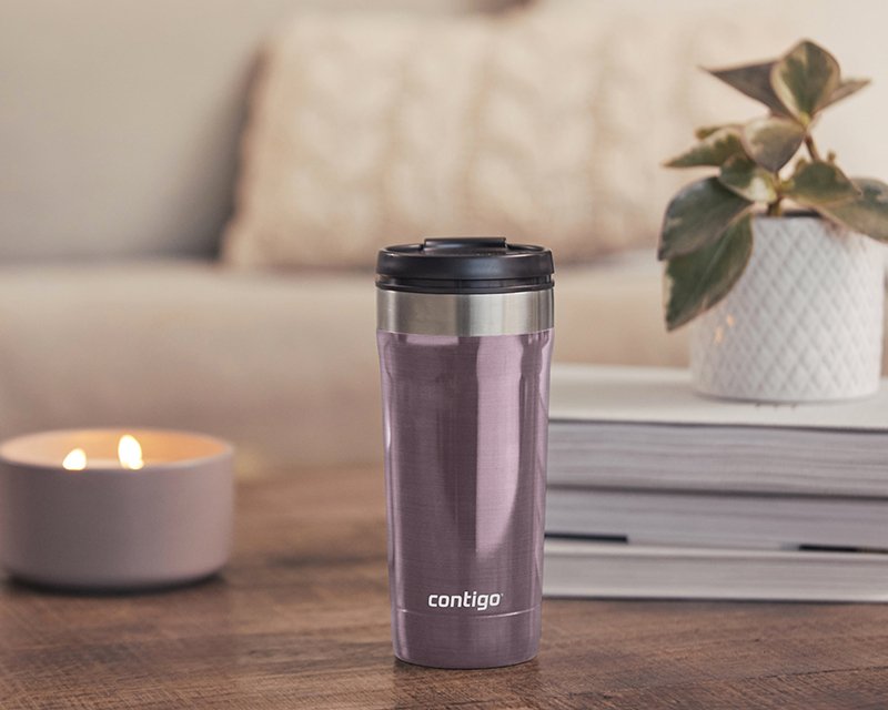 travel mug on table with candle