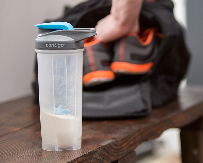 beverage container with protein powder in front of gym bag