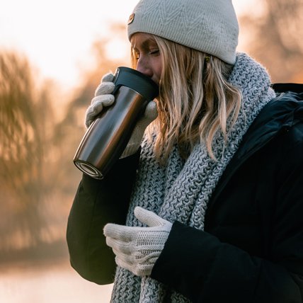 woman drinking from travel mug outdoors