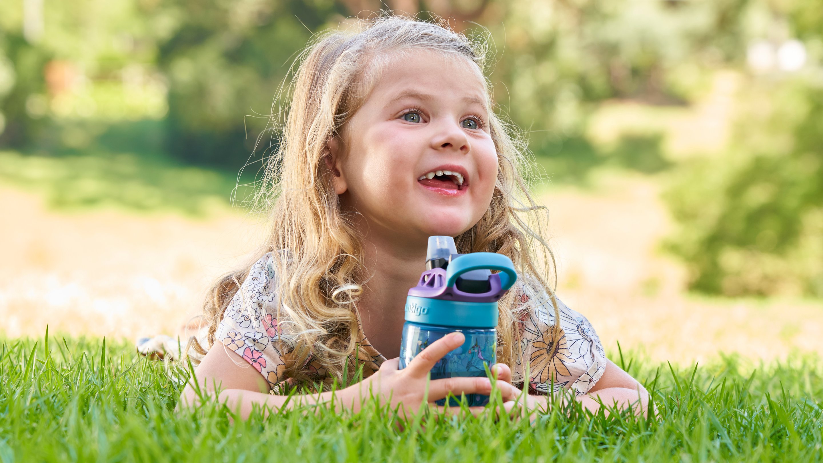 Child lying down outside holding a water bottle