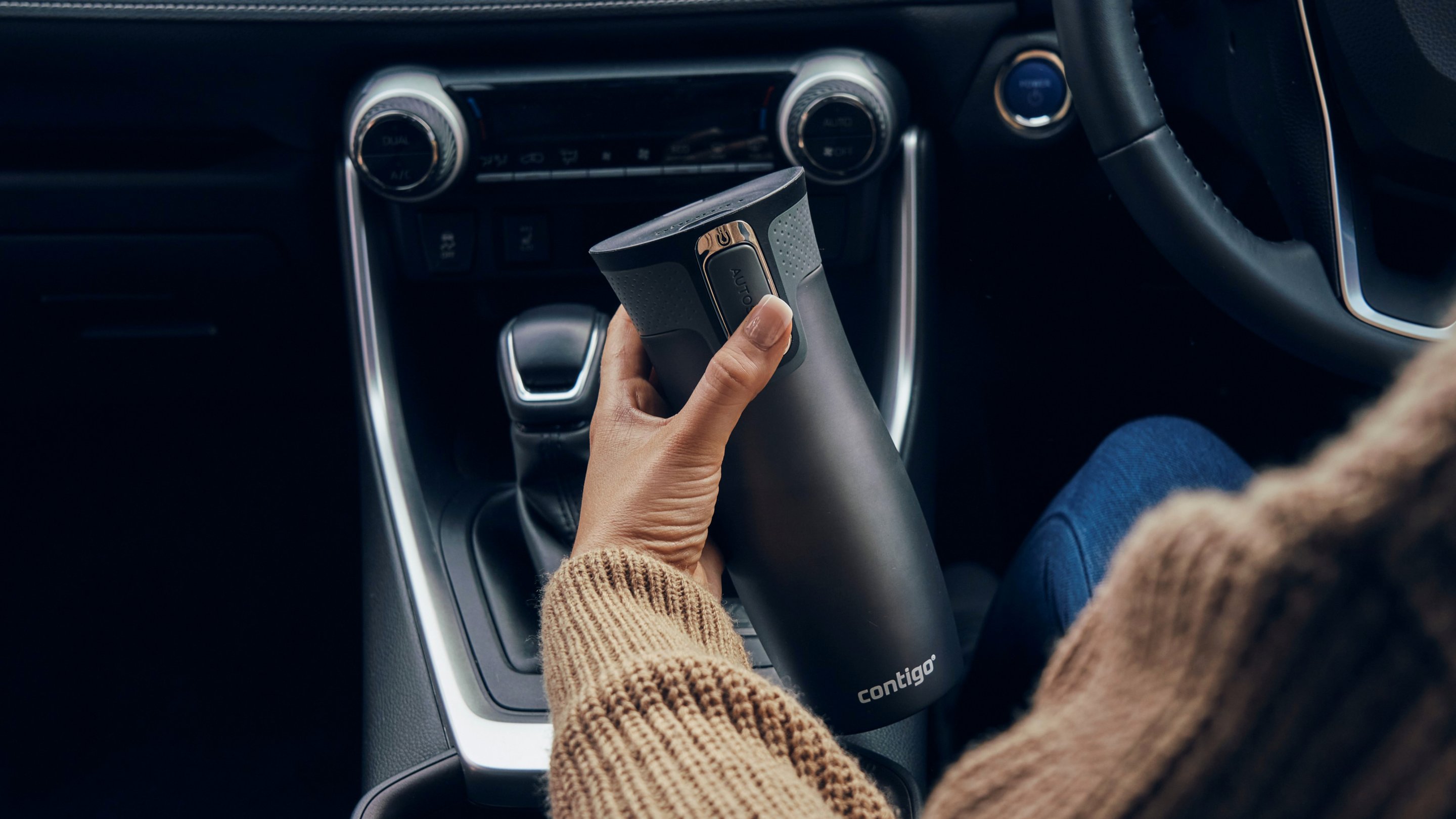 person holding travel mug in car
